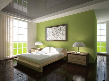 room wita a hardwood floor, bright windows on two sides, and a two-person bed with a bedside table and lamp on each side